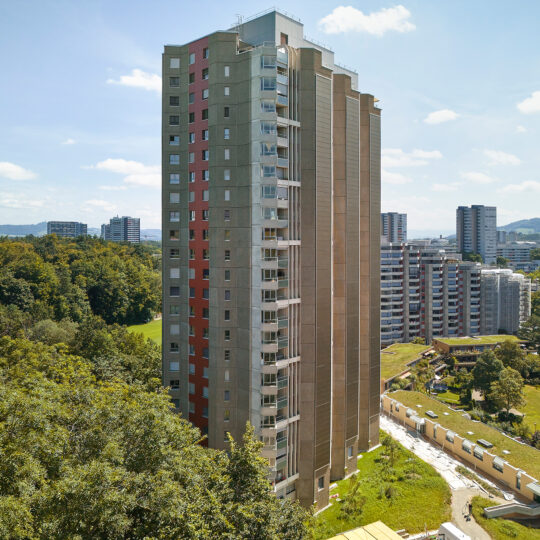 An aerial view of the Holenackerstraße high-rise in Bern, highlighting the large-scale implementation of a SKALA BIPV Bronze 3001 retrofit solar facade in an urban setting